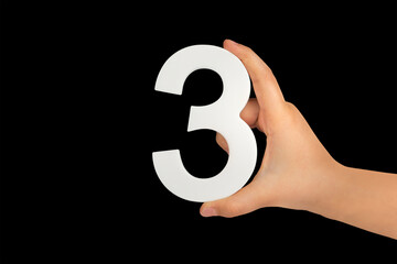 Aufkleber - number three in hand isolated on black background. Number three in a child's hand on a black background. To be inserted into a project or design.