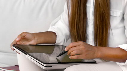 Working and study online on a tablet in a cafe. The girl draws on the tablet. Hands and tablet close-up