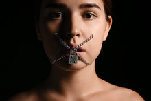 Young woman with locked mouth on dark background. Censorship concept