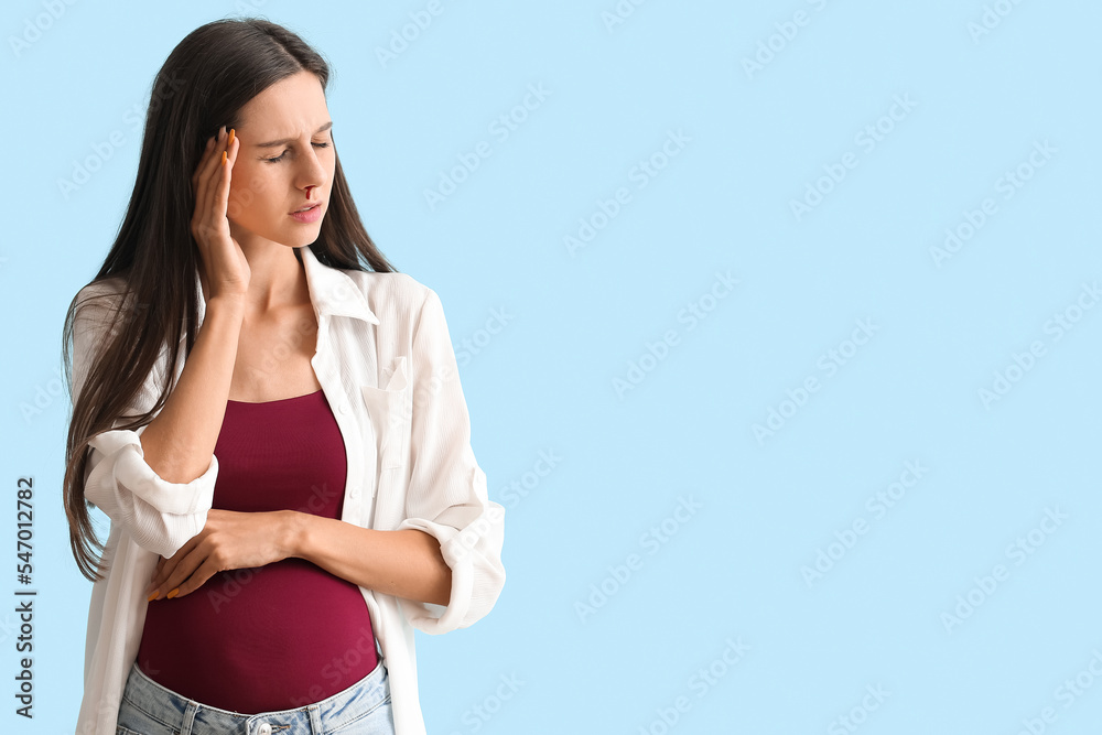 Young pregnant woman with nosebleed on blue background