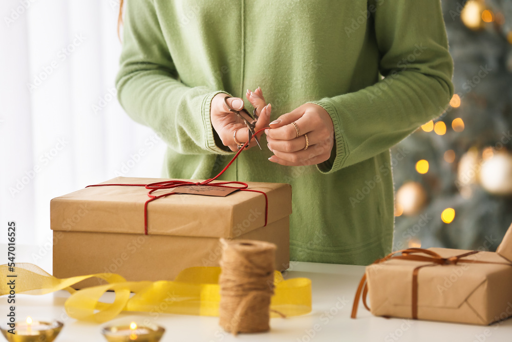 Woman packing Christmas gift box at table, closeup