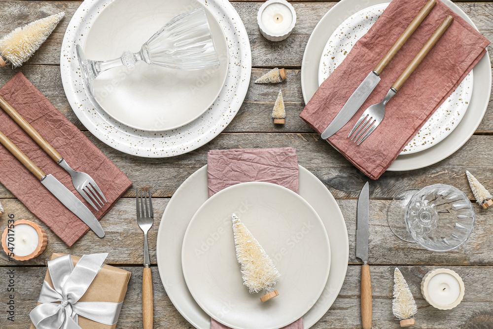Beautiful table setting with Christmas trees, gift and candles on wooden background