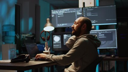 Male web programer writing code and dealing with back pain, sitting at office and feeling spinal discomfort at night. App developer coding html script on terminal window. Handheld shot.