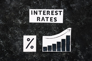 Interest rates text with percentage symbol and chart with stats increasing on dark background, economic struggles after the pandemic