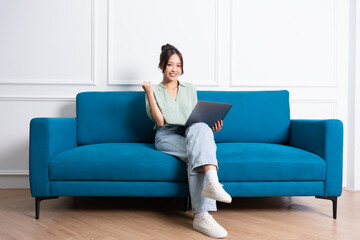 image of young Asian girl sitting on sofa at home