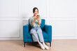 © Q88 - image of young Asian girl sitting on sofa at home
