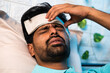 © WESTOCK - close up head shot of young indian sick man suffering from fever while sleeping at night by placing wet cloth on forehead - concept of healthcare, covid symptoms and illness.