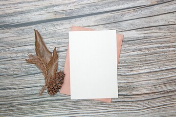 Top view of a blank sheet of paper with copy space and dried leaves on a wooden surface