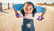 © Alexis S/peopleimages.com - Child, skateboard and excited for fun activity outdoor on promenade with smile, happiness and energy on summer vacation. Portrait of black girl with safety gear for elbow for skating or skateboarding