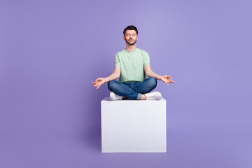 Poster - Full size photo of handsome young man sitting white copyspace cube meditating dressed stylish gray look isolated on purple color background