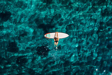 Surf Girl With Surfboard In Transparent Turquoise Ocean. Aerial Top View