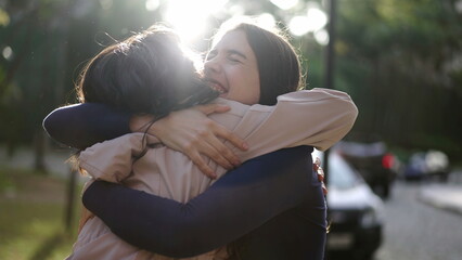 Two happy female best friends hugging each other. Women embrace reunion outdoors at park2