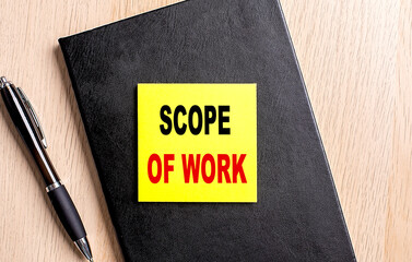 Poster - SCOPE OF WORK text on a sticky on black notebook with pen