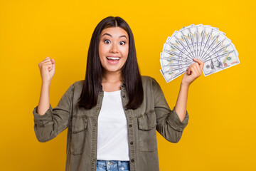 Sticker - Photo of young japanese khaki shirt woman satisfied excited raise fist up winner jackpot money dollars hooray isolated on yellow color background