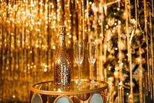 Champagne Bottle And Glasses Against Luxury Glow Golden Rain Decoration Expensive Holidays Party