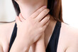 A woman suffering from esophagitis is touching her wrinkled neck.