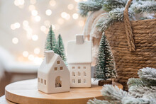 A Bouquet Of Fir Trees, A Plaid In A Wicker Basket And Scandinavian White Houses On A Wooden Table In The Home Interior Of The Living Room. A Cozy Concept Of Festive Home Decoration.