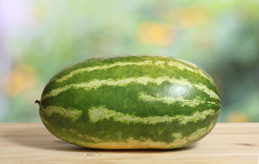 Wall Mural - Fresh Watermelon on Wooden Table With Green Nature Blur Background