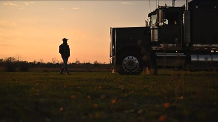 Wall Mural - Semi Truck Driver in Front of His Vehicle During Scenic Countryside Sunset. Transportation Industry Theme.