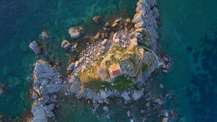 Wall Mural - Slowmotion aerial video. The Sveta Nedelja - Christian church on a tiny island in the sea close to the city of Petrovac Lots of martlets fly over the island