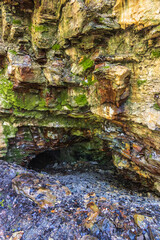 Canvas Print - Colorful rock face and a cave to the underground