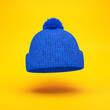 © salamahin - Blue knitted hat floating on a yellow background, 3d render