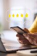© Monkey Business - Man Using Mobile Phone With Graphic Overlay To Leave Positive 5 Star Online Review