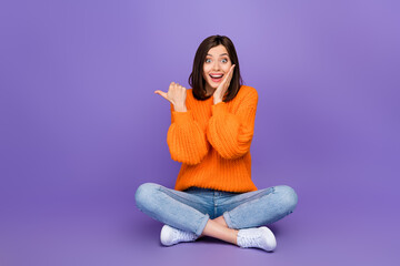 Canvas Print - Full size photo of nice young girl impressed point copyspace sit floor wear trendy knitwear orange look isolated on violet color background