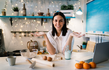 Happy woman with arms apart cooking in kitchen