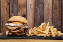 Multilayer Burger With Grilled Meat, Provolone Cheese, Onion Rings Bacon, Bbq Sauce And A Grilled Egg.
