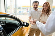 Couple getting car remote control unit from salesperson