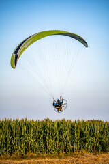 Wall Mural - Closeup of a man doing a paramotor flight paragliding over the corn fields