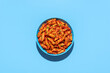 Penne pasta in tomato sauce, top view on a blue background