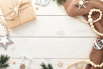 Frame of neutral Christmas decorations on white wooden desk table. Xmas greeting card template, cover, banner design.