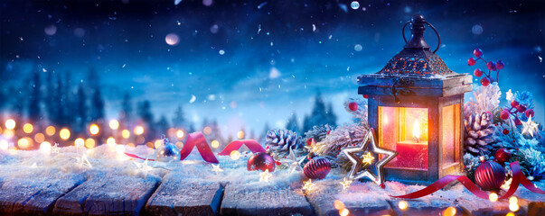 Wall Mural - christmas lantern with decoration on snow table - snowy candle light and abstract defocused landscap