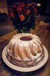 Freshly baked homemade delicious bundt cake covered in sugar powder on a table in front of flowers