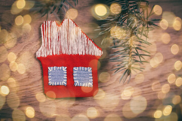 concept of Christmas.knitted house and pine branch on wooden bac