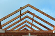 A timber roof truss in a house under construction, walls made of autoclaved aerated concrete blocks, a rough window opening, a reinforced brick lintel, blue sky in the background