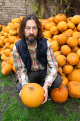 Poster - Bearded farmer with pumpkin on a background of a pile of pumpkins