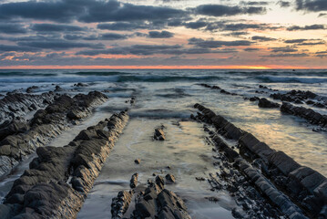 Wall Mural - Beautiful sunset landscape image of Welcome Mouth Beach in Devon England with beautiful rock formations