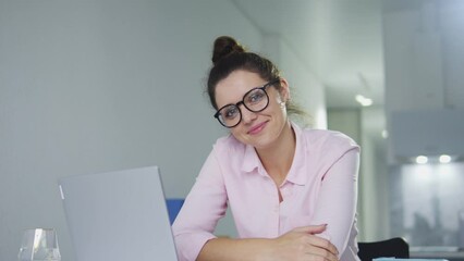 Female editor of famous magazine smiling and posing at workplace with laptop