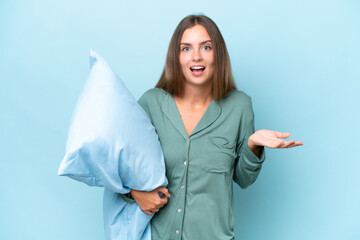 Poster - Young beautiful woman isolated on blue background in pajamas and with shocked facial expression