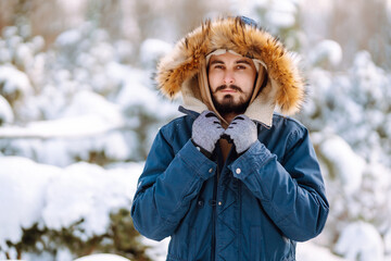 Wall Mural - Young man in snowy winter forest. Season, christmas, travel and people concept.