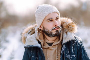 Wall Mural - Young man in snowy winter forest. Season, christmas, travel and people concept.