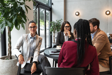 Group of young successful business people small new company owners staff meeting and teambuilding in cafeteria, discussing about ideas and solutions of job improvement  and better sale performance. 