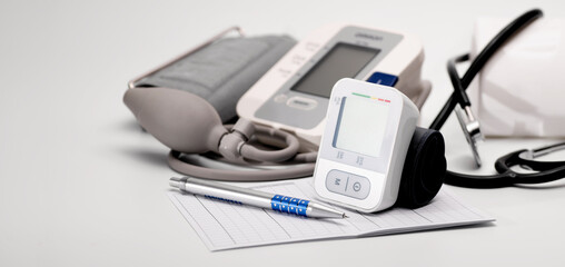 Wall Mural - Tonometers, brachial and automatic digital wrist sphygmomanometer, stethoscope, lie on the table, pressure diagnostics, on a white background, banner