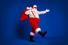 Full Length Body Size View Of His He Attractive Cheerful Cheery Funny Fat Santa Carrying Big Large Sack Delivery Sale Going Isolated Bright Vivid Shine Vibrant Red Color Background