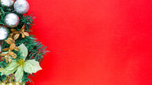 Part Of Christmas Wreath With Glittering Balls And Gold Leaves On Red Background With Copy Space In Top View