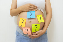 Close Up Pregnant Woman With Question Marks On Tummy, Concept Of Pregnancy, Choosing Baby Name