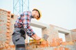 © Serhii - Construction worker man in work clothes and a construction helmet. Portrait of positive male builder in hardhat working at construction site.